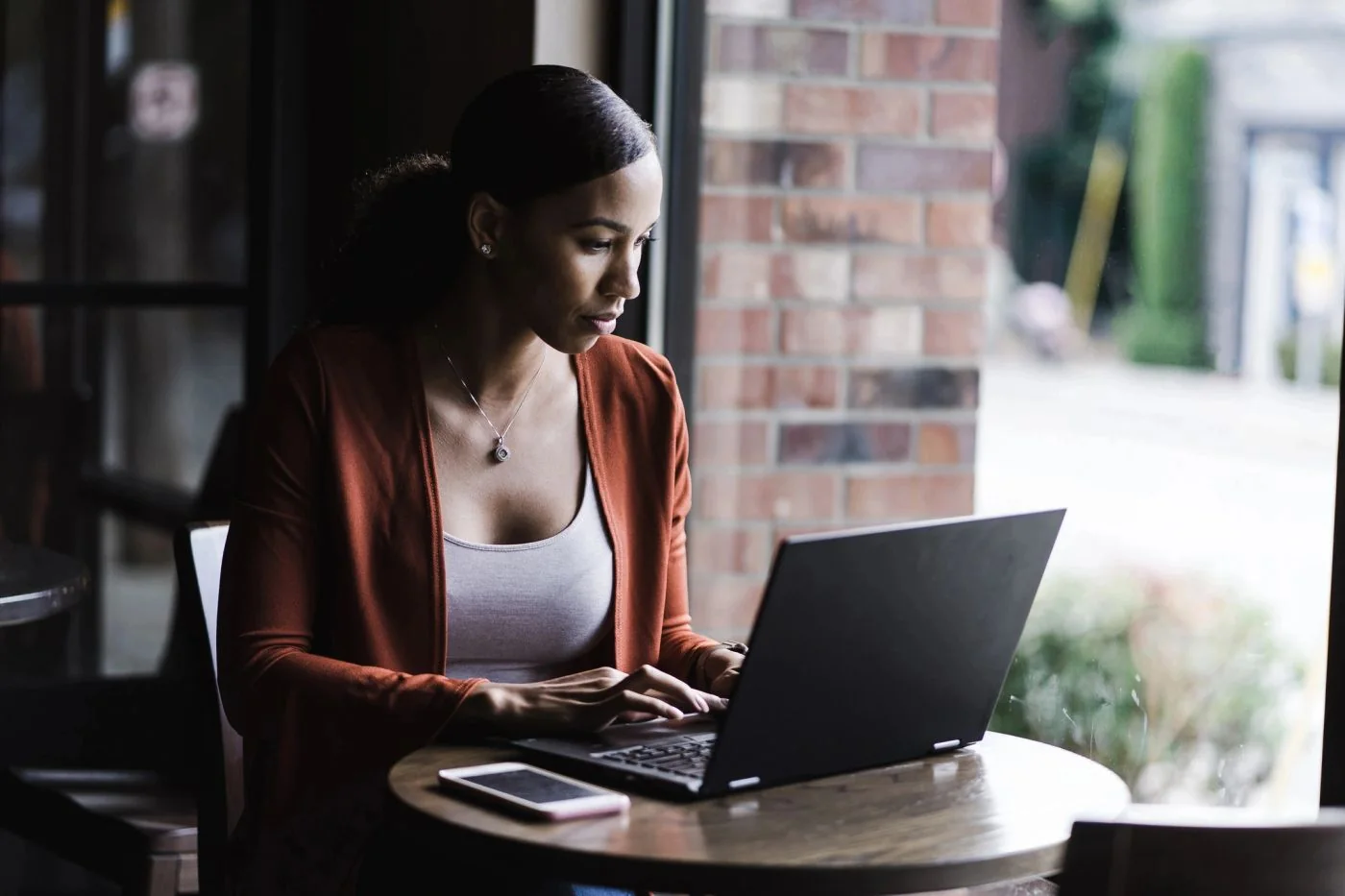 Professional using a laptop beside a café window